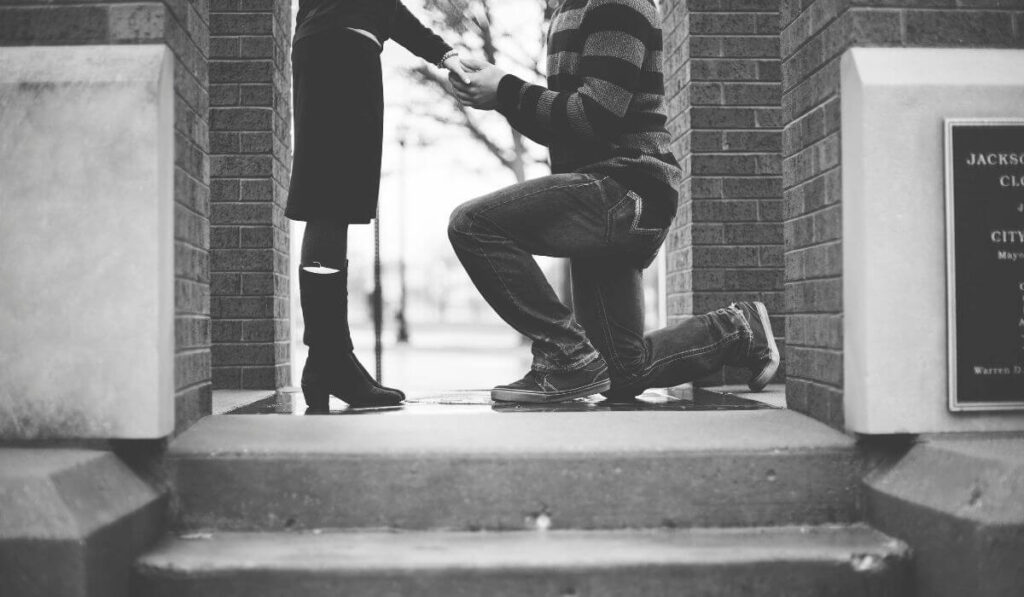 A black and white image of a romantic proposal in Chicago, featuring a person kneeling on one knee.