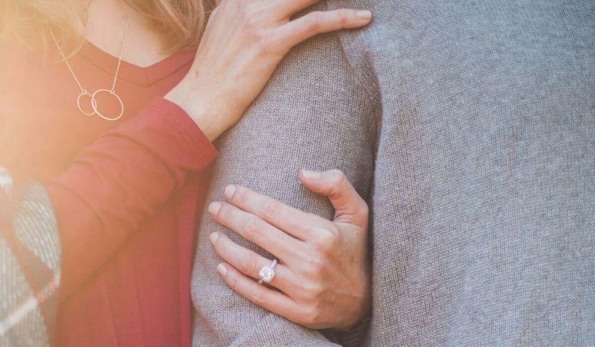 A close-up of a couple embracing, with a sparkling engagement ring symbolizing joyful marriage proposals.