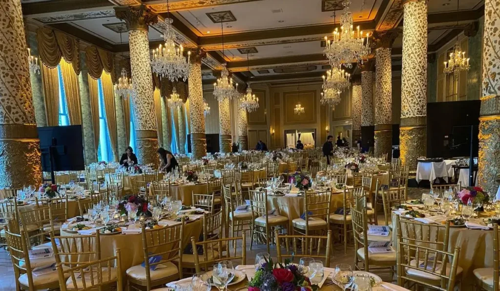 A stunning luxury wedding venue decorated with chandeliers, gold chairs, and floral arrangements for a glamorous celebration.