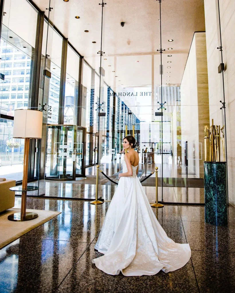 A stunning bride poses elegantly at a luxury Chicago wedding venue with glass walls and city views.