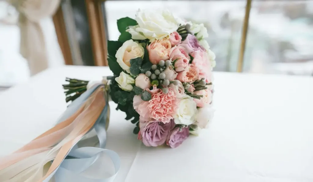 Elegant pastel bridal bouquet with roses and ribbons, perfect for capturing the beauty of the wedding day.