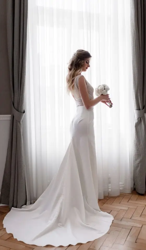 Elegant bride showcasing a fitted gown with a seamless wedding dress bustle highlighting her graceful silhouette indoors.