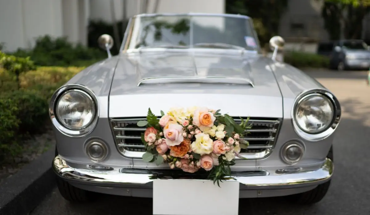 Classic silver wedding car decorated with floral arrangement, offering elegant and timeless wedding transportation for couples.