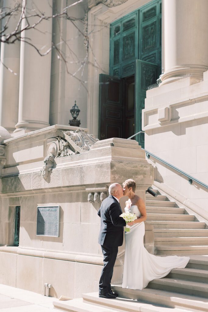 Couple kissing on grand steps of historic building with columns and green door