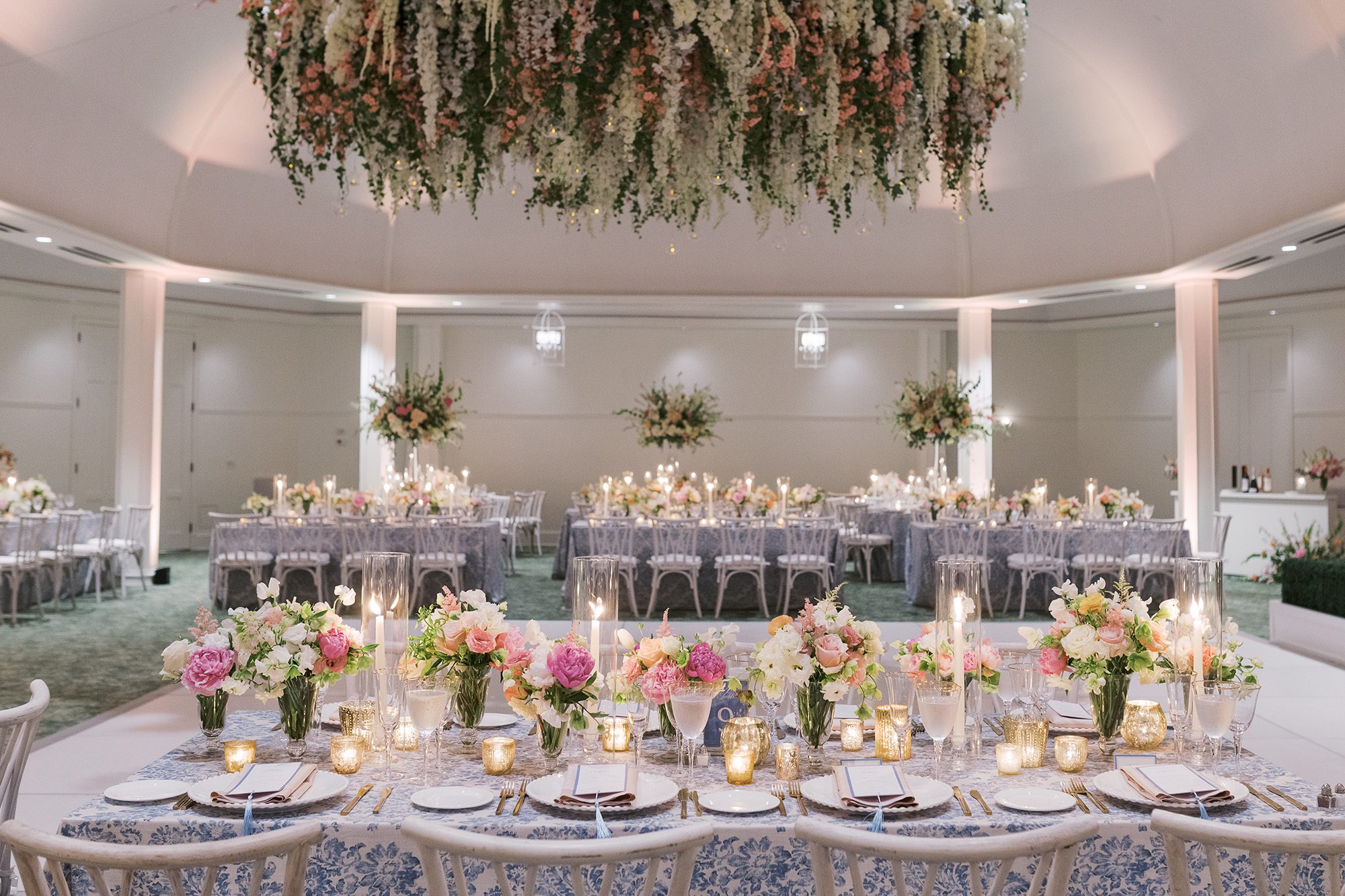 Elegant wedding reception featuring floral ceiling installation, patterned linens, and candlelit centerpieces — styled by our full service wedding planning team in Chicago