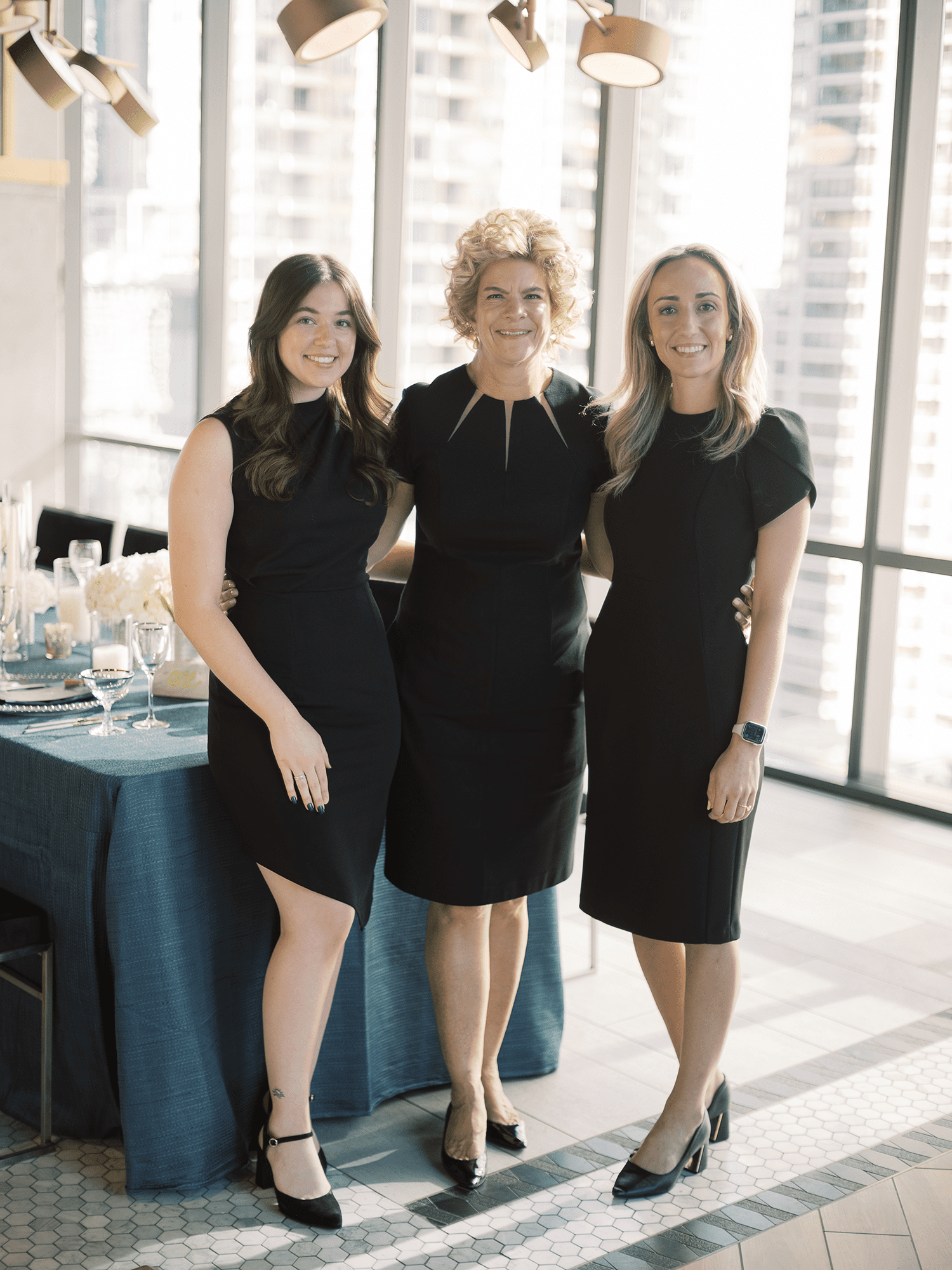 three event planners in black dresses standing infront of table at corporate retreat Chicago