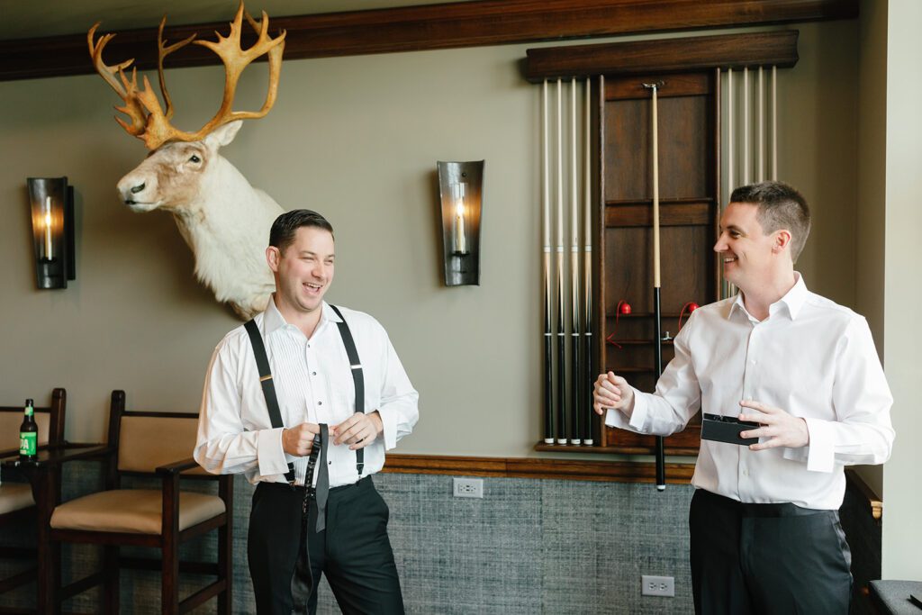 Groom getting ready in lounge with pool cues, antler decor, and relaxed pre-ceremony energy at chicago wedding venue.
