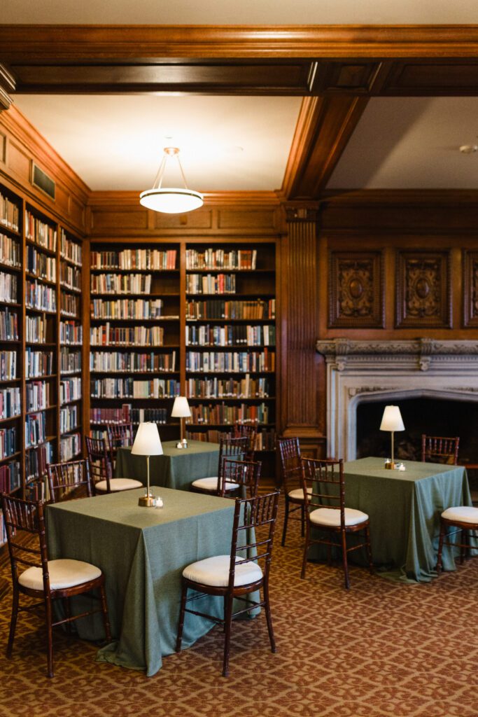 Library room at the university club in Chicago with wood bookshelves, green tables, fireplace, and warm ambient lighting.