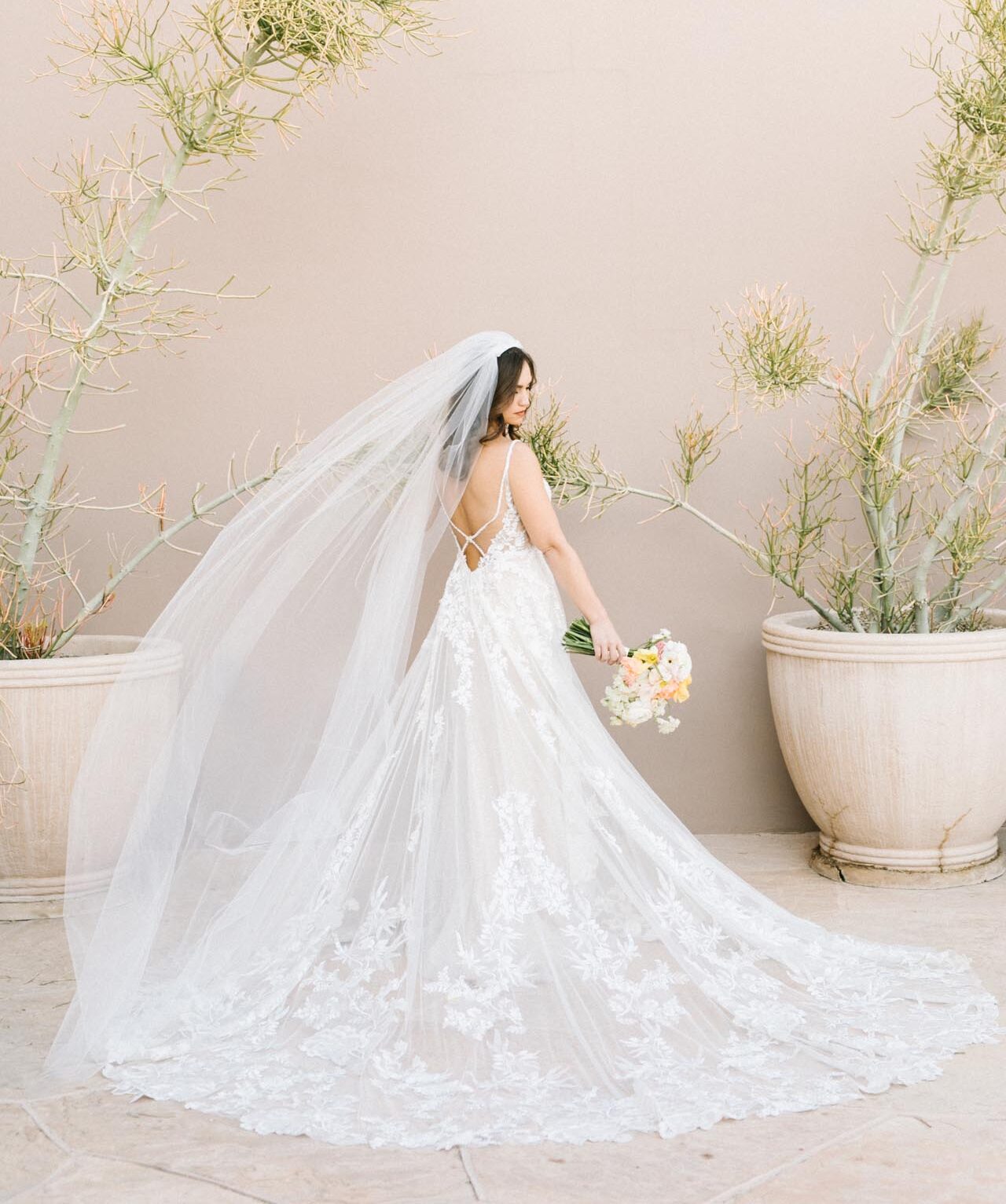 Bride in lace gown with bouquet and veil standing outdoors in Scottsdale