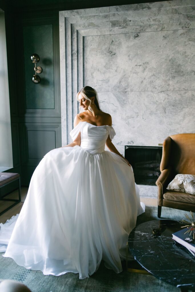 Elegant bridal portrait in a marble‑paneled lounge featuring a fireplace, modern furnishings, and editorial lighting.