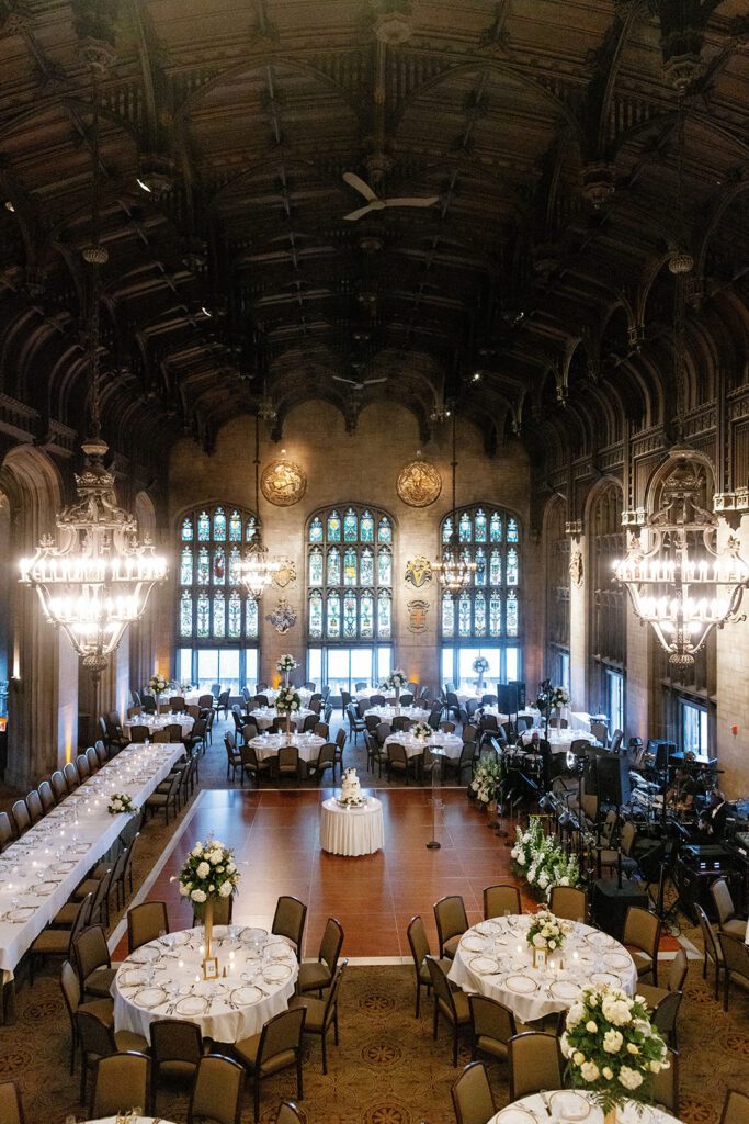 Cathedral Hall set for a luxury wedding reception with chandeliers, floral tables, and a central cake display.