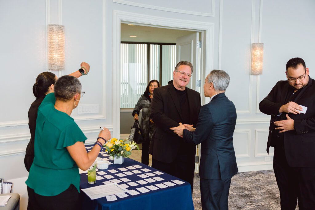 Two attendees pose at a formal networking event with drinks and name tags, captured by a nonprofit event planner during a donor engagement program.