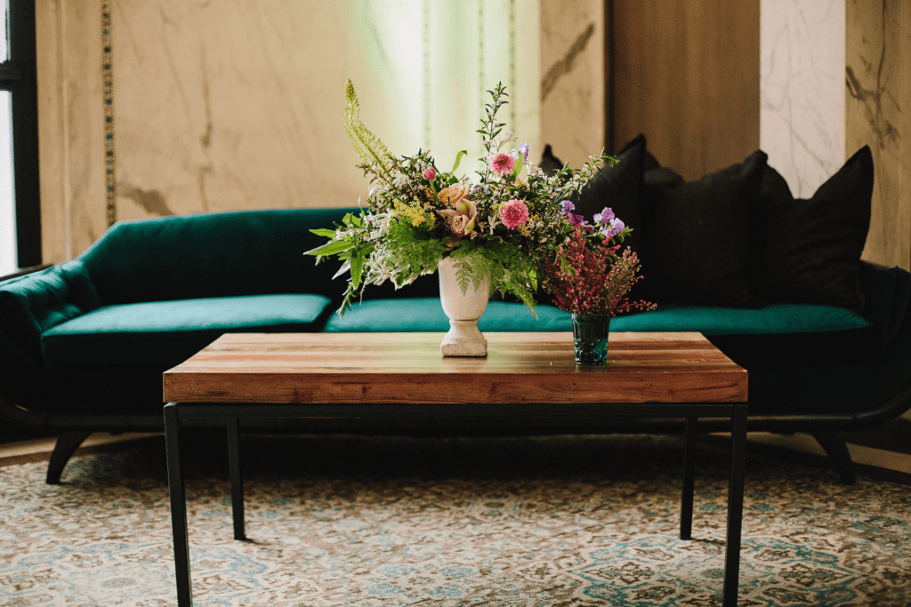 Floral arrangements on a coffee table in front of a velvet sofa in a marble-paneled lounge at the Chicago Cultural Center, perfect for getting-ready portraits.