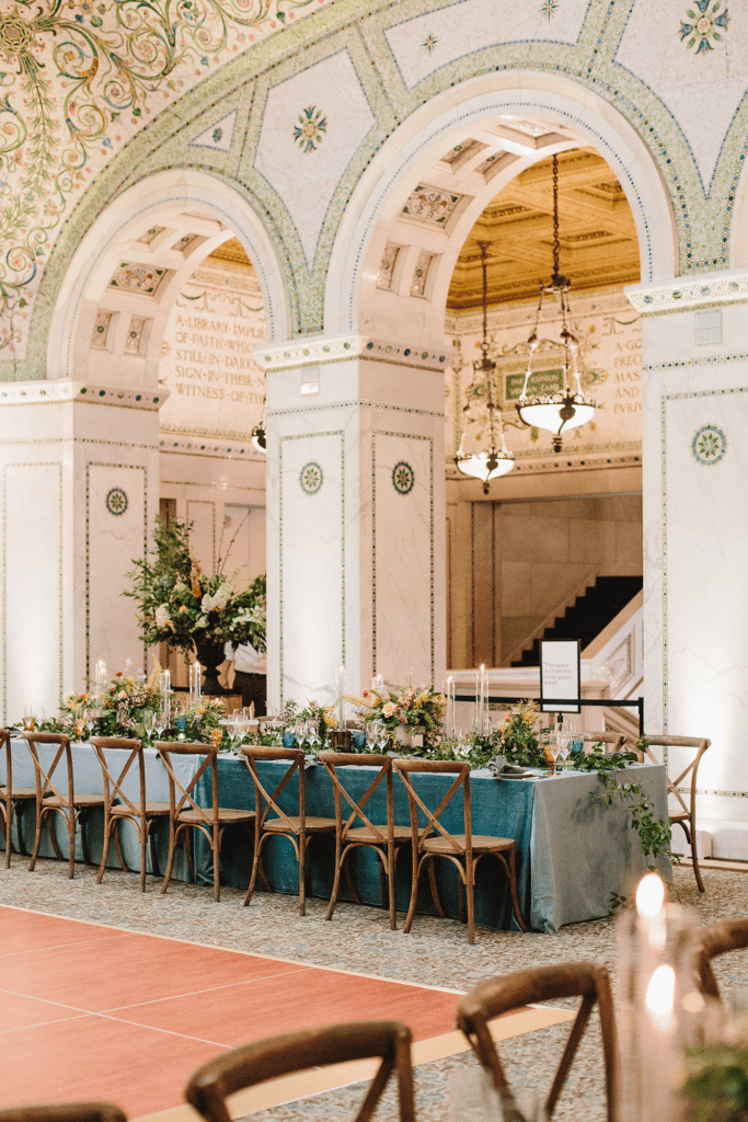 Long banquet table with teal linens and floral decor set beneath mosaic arches in the Rotunda, ideal for cocktail hour or intimate dining at the Chicago Cultural Center.