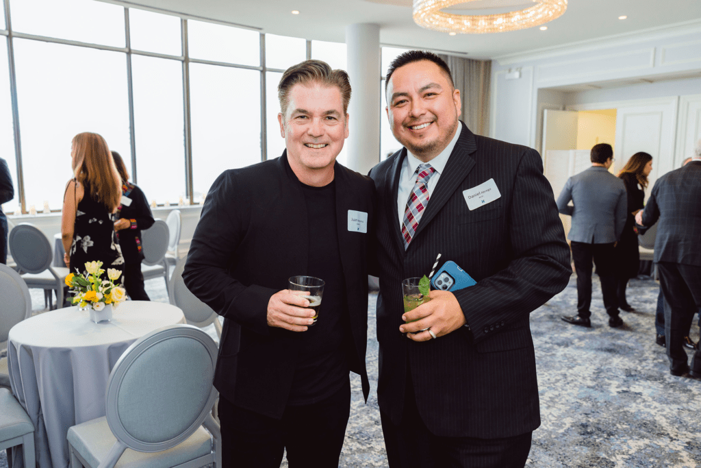 Two attendees pose at a formal networking event with drinks and name tags, captured by a nonprofit event planner during a donor engagement program.