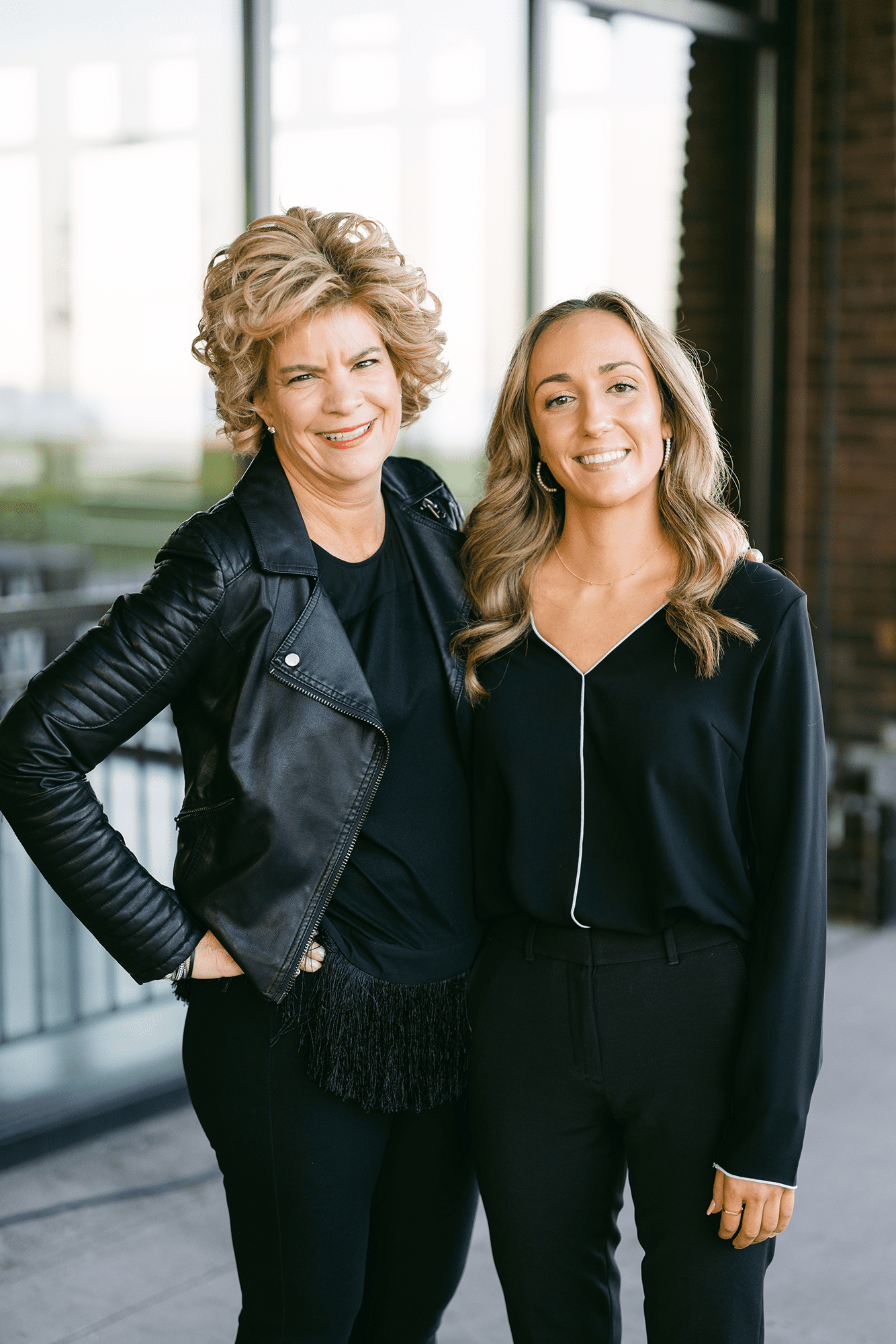 Two Chicago party planners from Effortless Events standing outside a modern venue, dressed in black with polished styling and warm smiles.