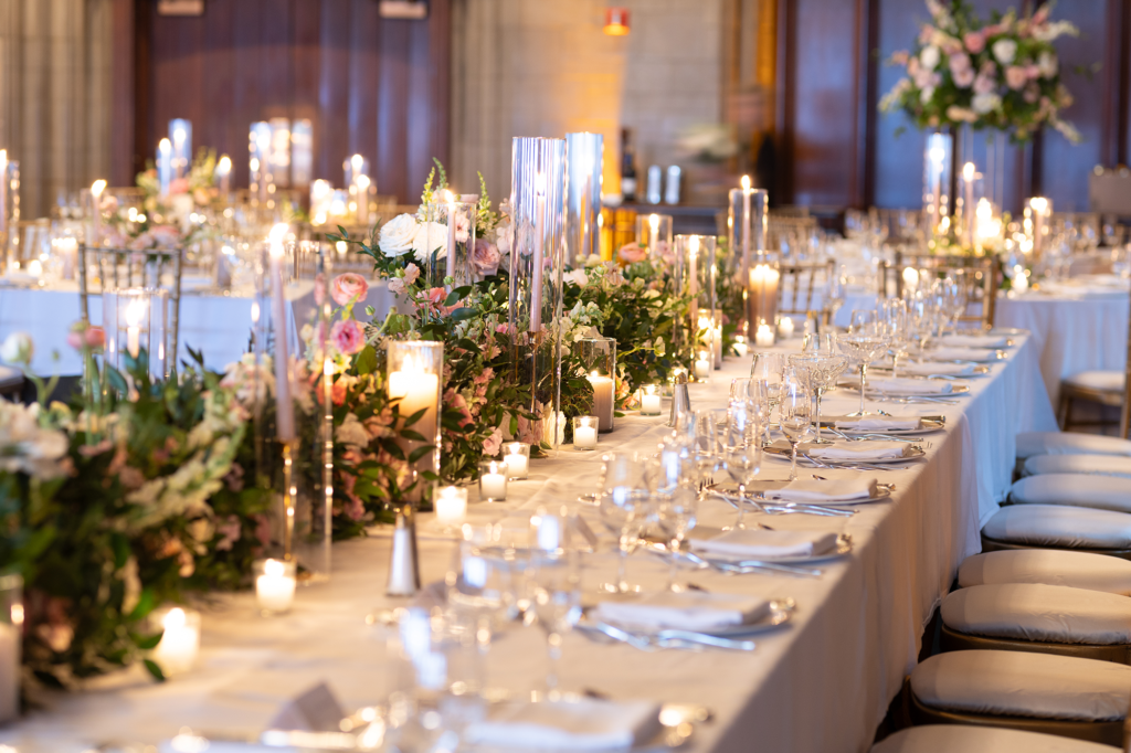 Long banquet table at upscale chicago wedding with pink and white florals, candles, and elegant place settings.