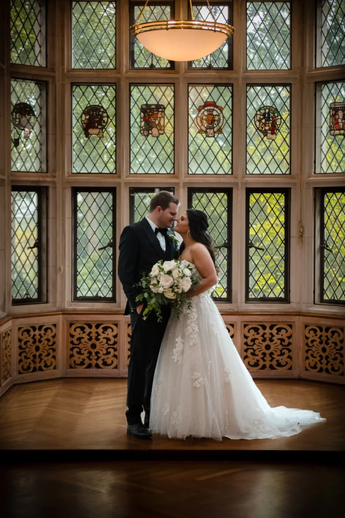 bride and groom kissing in founders room with stained glass windows