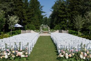 Elegant Morton Arboretum wedding ceremony with white chairs, floral aisle, and garden backdrop framed by classical columns.