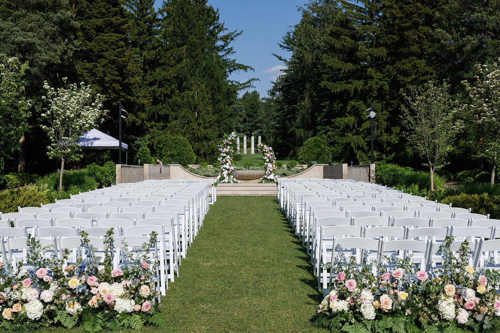 Elegant Morton Arboretum wedding ceremony with white chairs, floral aisle, and garden backdrop framed by classical columns.