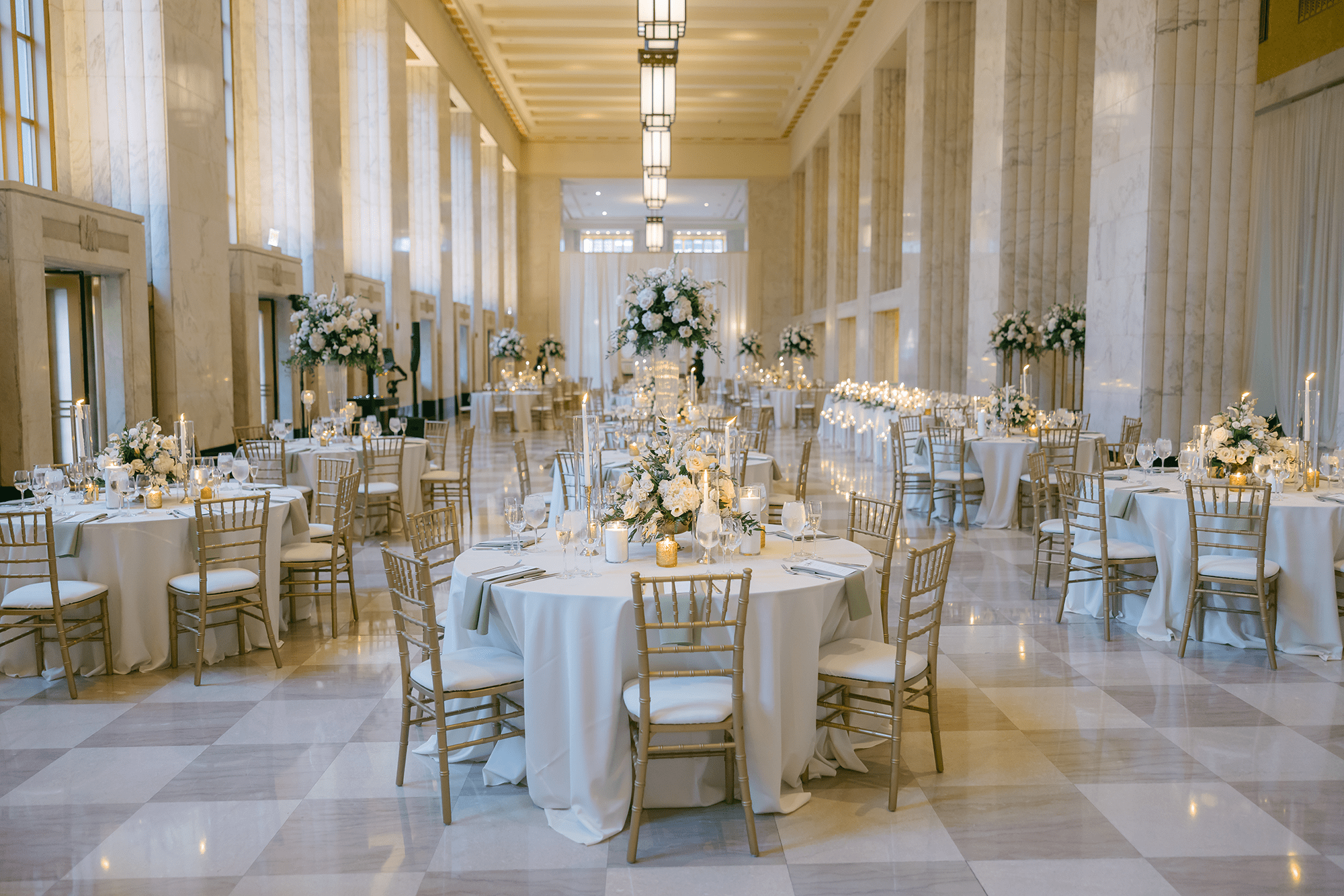 Luxurious Old Post Office Chicago wedding reception featuring gold Chiavari chairs, white and blush floral centerpieces, marble columns, and soaring ceilings
