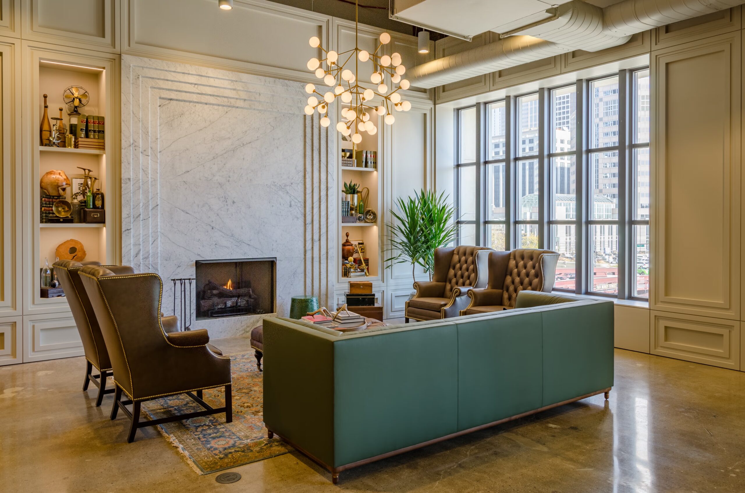 Sophisticated lounge at the Old Post Office featuring a marble fireplace, tufted leather sofas, green paneling, and a mirrored bar with gold accents.