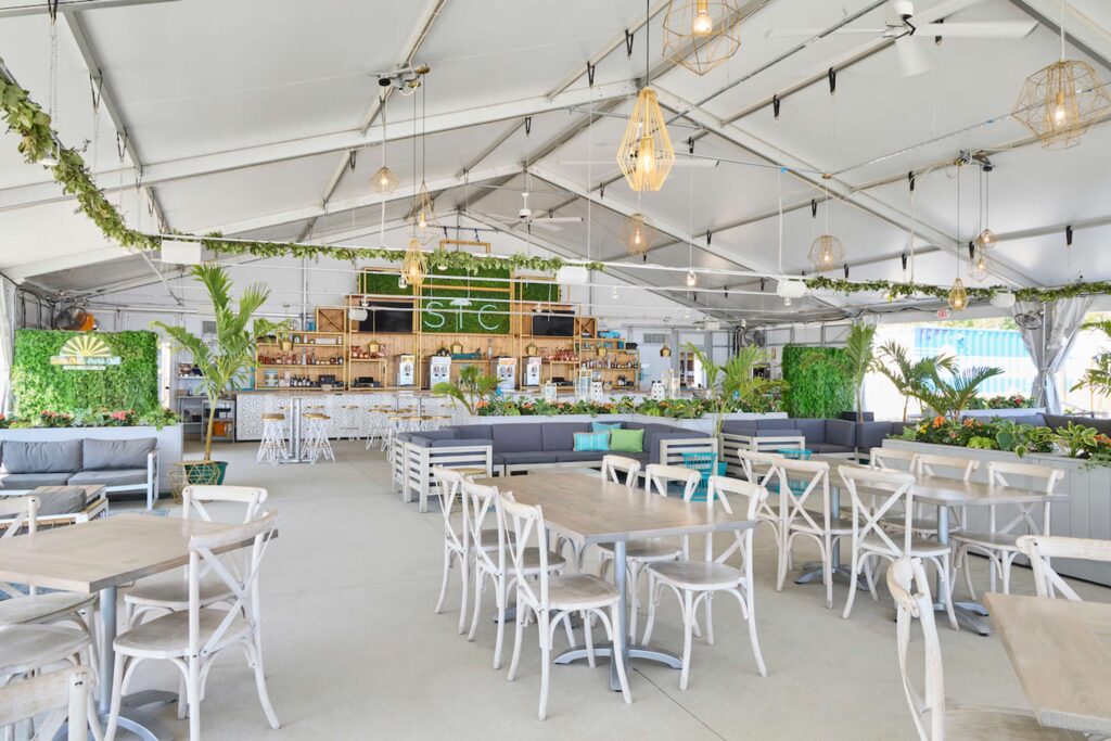 open-air lounge at Shore Club Chicago featuring tropical greenery, wood furniture, and a modern tented structure.
