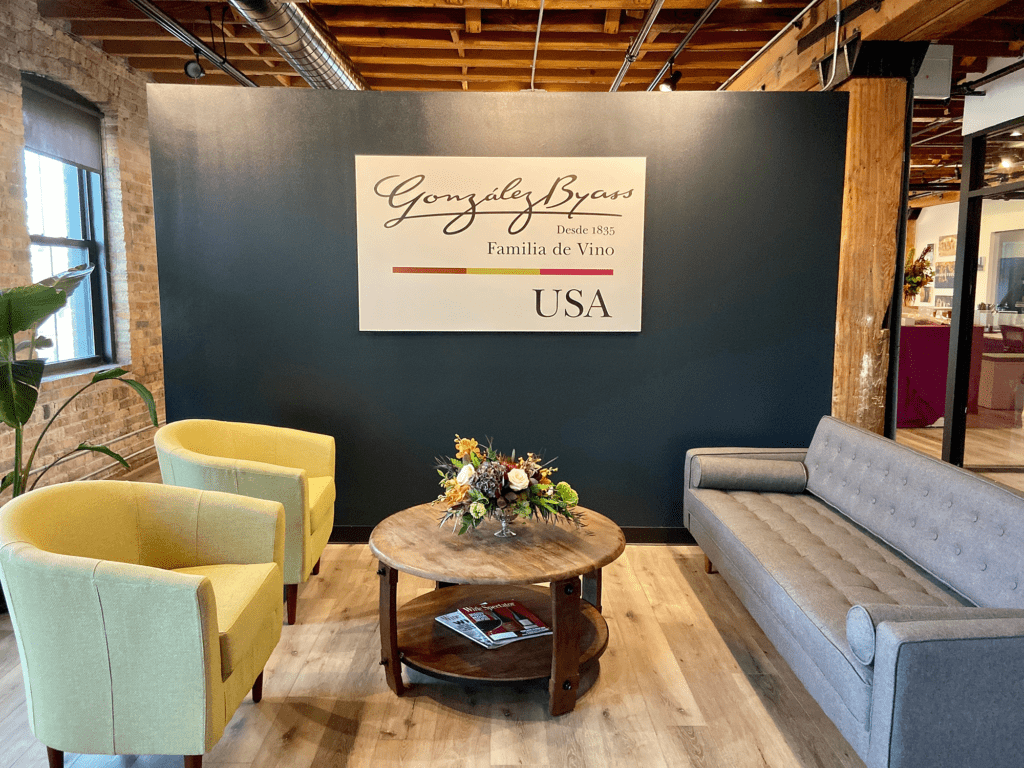 Cozy lounge with yellow armchairs, floral centerpiece, and rustic-industrial design at a wine company reception area.