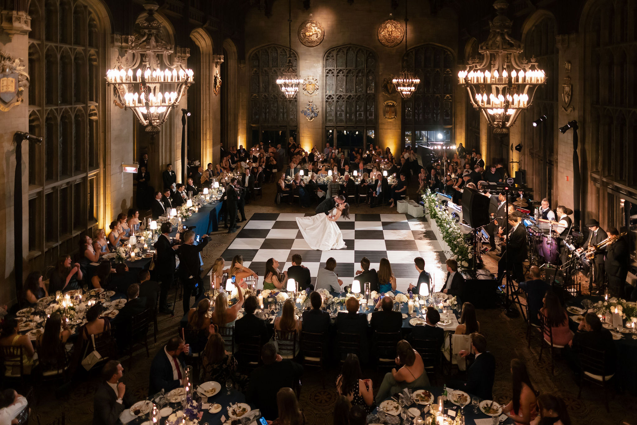 Bride and groom share their first dance at an elegant University Club of Chicago wedding reception with a black and white dance floor, candlelit tables, and grand gothic architecture