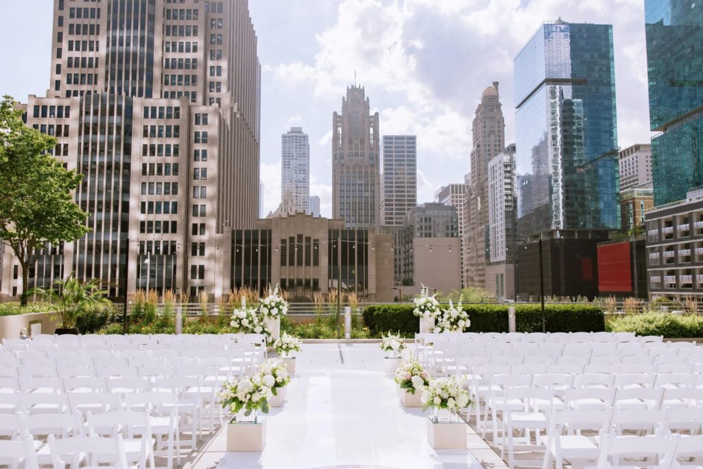 Outdoor rooftop wedding ceremony at Loews Chicago Hotel with white florals, ceremony seating, and panoramic views of the Chicago skyline.