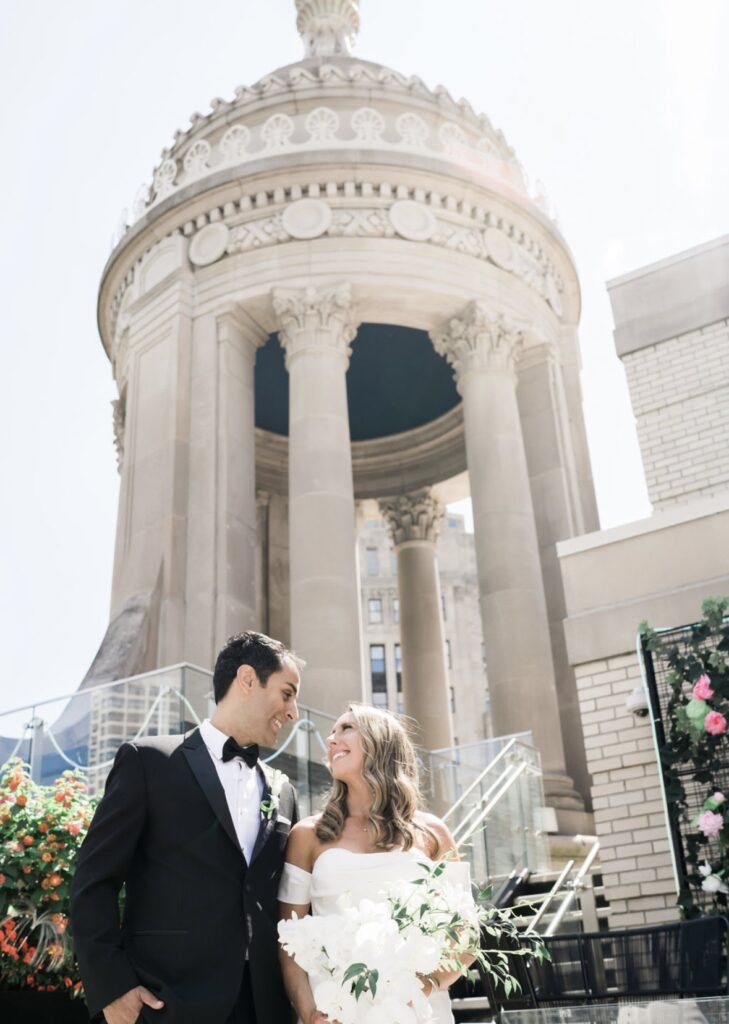 Bride and groom on the LondonHouse Chicago rooftop with the venue’s iconic cupola and downtown Chicago architecture in the background