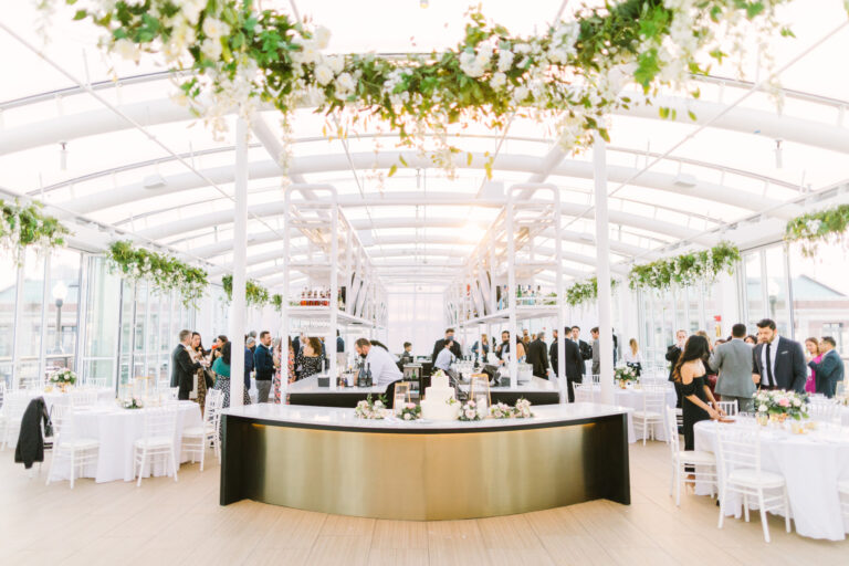 Elegant wedding reception inside Offshore Rooftop at Navy Pier in Chicago featuring white florals, hanging greenery, and a bright modern indoor event space.