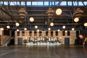 Industrial Chicago venue with exposed beams, floral mural, and stocked bar for creative events and receptions.