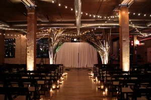 Candlelit Chicago wedding ceremony in a rustic-industrial venue with floral arch, string lights, and exposed brick.