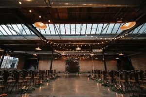 Industrial-chic Chicago ceremony with skylights, string lights, and a floral arch for warm, romantic weddings.