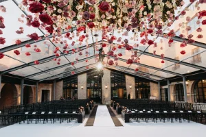 Romantic Chicago wedding ceremony under a glass ceiling with hanging roses, chandeliers, and candlelit aisle.