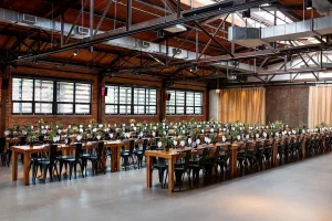 Industrial Chicago banquet venue with exposed brick, floral centerpieces, and long wooden tables for formal dinners.