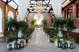 Industrial-chic Chicago ceremony with brick walls, glass ceiling, and lush greenery for elegant weddings.