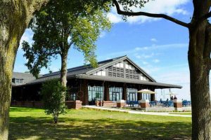 Scenic Chicago venue with glass architecture, shaded lawn, and water views for relaxed outdoor events.